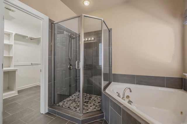 bathroom featuring a spacious closet, visible vents, a stall shower, and a whirlpool tub