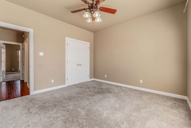 unfurnished bedroom with a closet, baseboards, dark carpet, and ceiling fan