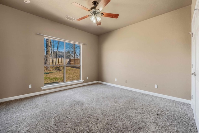 carpeted empty room featuring visible vents, a ceiling fan, and baseboards