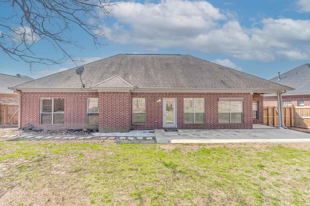 back of house with brick siding, fence, roof with shingles, a yard, and a patio area