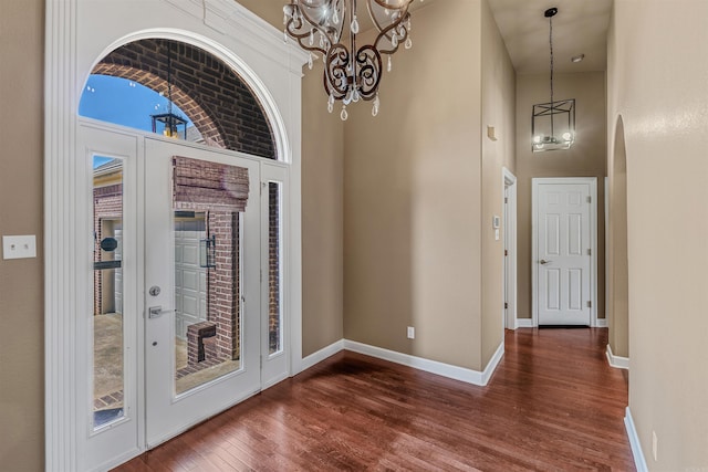 entryway with baseboards, a notable chandelier, a towering ceiling, and dark wood finished floors