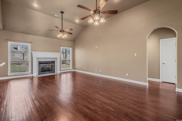 unfurnished living room with dark wood-style floors, visible vents, baseboards, a fireplace with flush hearth, and arched walkways