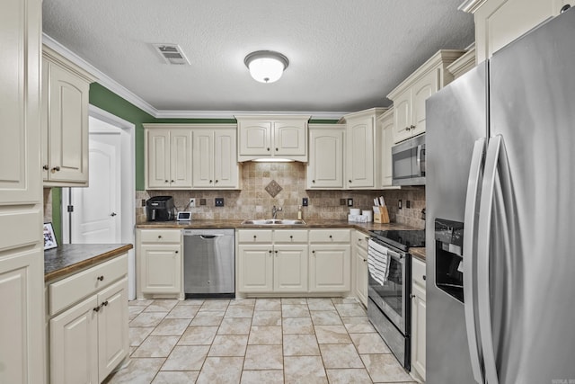 kitchen with visible vents, a sink, stainless steel appliances, dark countertops, and backsplash