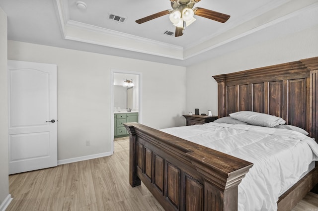 bedroom featuring visible vents, a raised ceiling, light wood-style floors, and ornamental molding