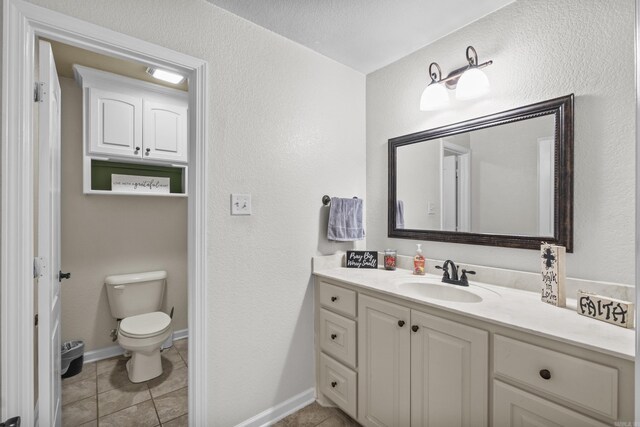 bathroom featuring tile patterned floors, baseboards, toilet, and vanity