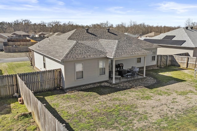 rear view of house with a yard, a fenced backyard, a shingled roof, and a patio