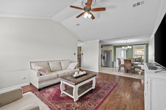 living area with dark wood finished floors, vaulted ceiling, visible vents, and ornamental molding