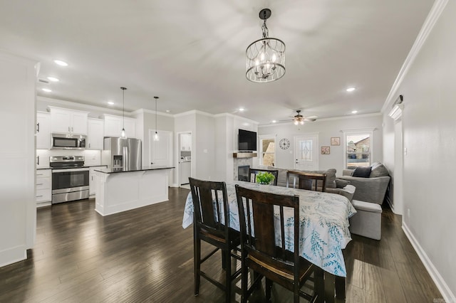 dining room with baseboards, recessed lighting, dark wood-style flooring, a glass covered fireplace, and crown molding