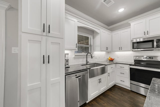 kitchen with visible vents, a sink, decorative backsplash, stainless steel appliances, and white cabinets