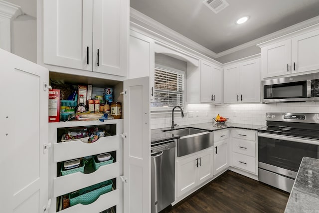 kitchen featuring visible vents, a sink, tasteful backsplash, dark wood finished floors, and stainless steel appliances