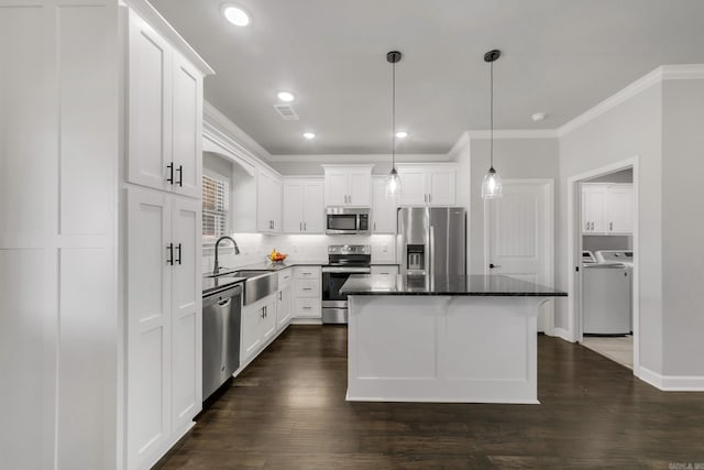 kitchen with separate washer and dryer, a sink, appliances with stainless steel finishes, white cabinetry, and crown molding