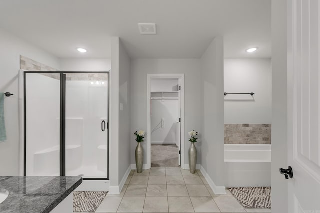 bathroom featuring visible vents, a garden tub, a shower stall, baseboards, and a spacious closet