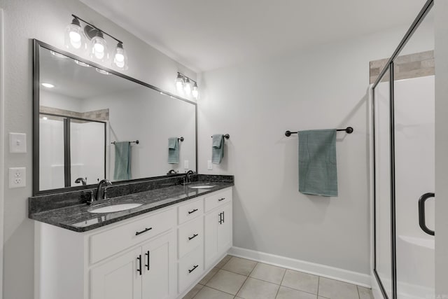 bathroom featuring tile patterned floors, a stall shower, double vanity, and a sink