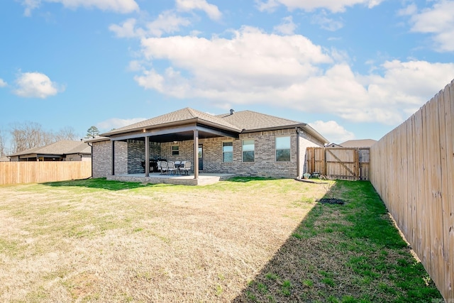 back of house featuring a patio, a gate, a yard, a fenced backyard, and brick siding