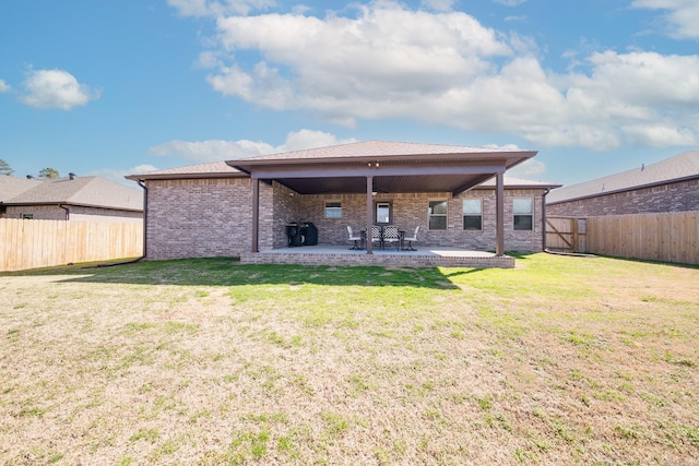 back of house with a lawn, a fenced backyard, brick siding, and a patio area