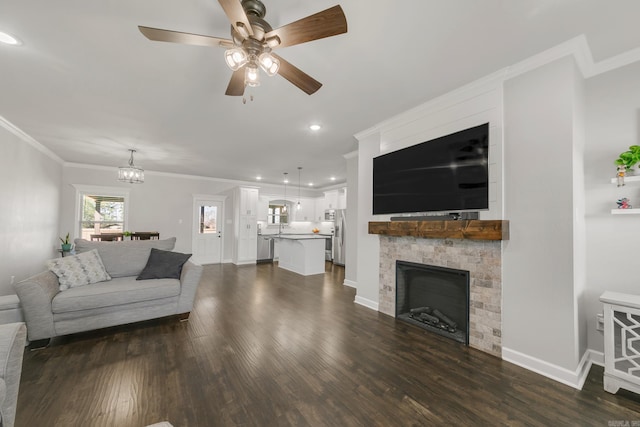 living room featuring dark wood finished floors, ceiling fan with notable chandelier, baseboards, and ornamental molding