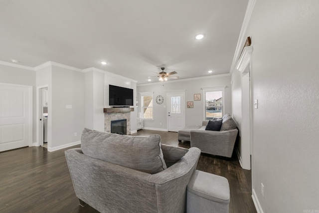 living room with dark wood finished floors, a glass covered fireplace, baseboards, and ornamental molding