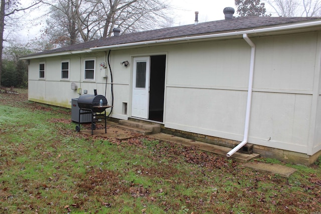 rear view of property featuring a lawn and a shingled roof