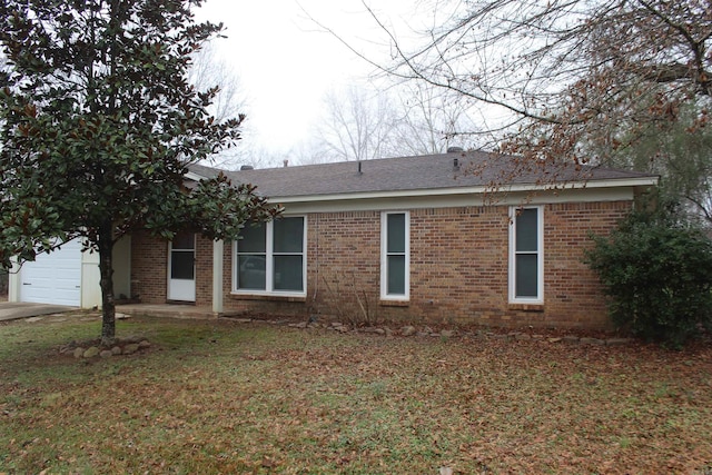 view of home's exterior featuring brick siding, an attached garage, and a lawn