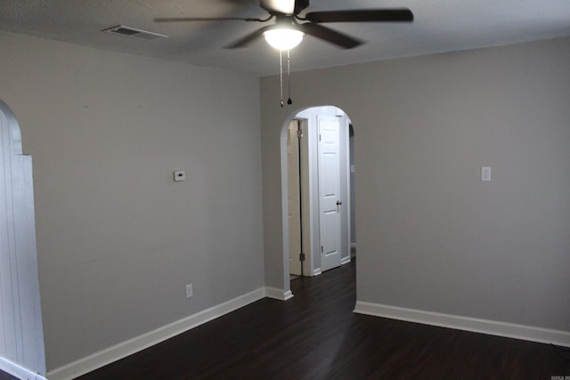 empty room featuring arched walkways, visible vents, dark wood-type flooring, and ceiling fan