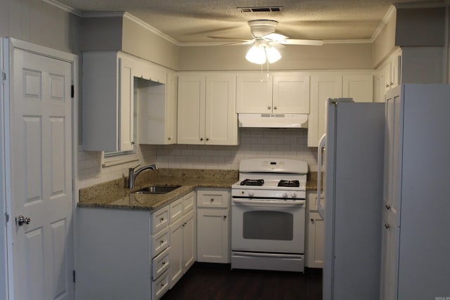 kitchen with white appliances, dark stone counters, a sink, under cabinet range hood, and crown molding