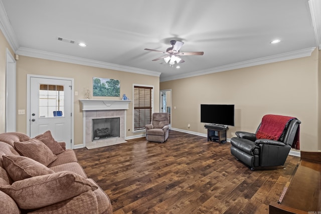 living room featuring a tiled fireplace, dark wood-type flooring, crown molding, and visible vents