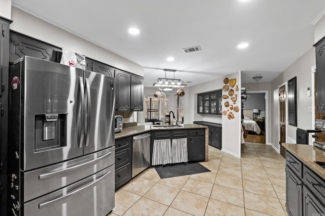 kitchen with visible vents, a peninsula, light tile patterned flooring, stainless steel appliances, and a sink