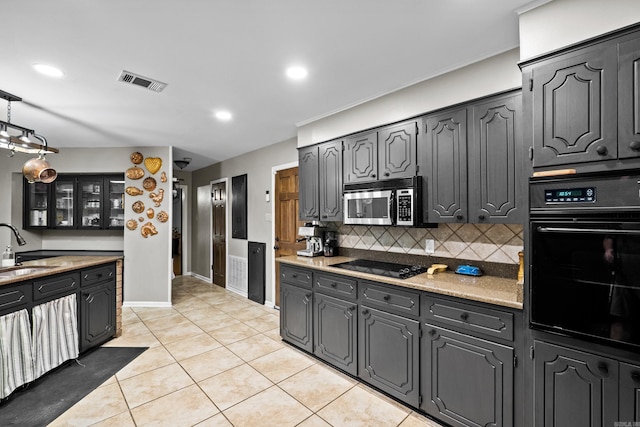 kitchen featuring visible vents, a sink, black appliances, glass insert cabinets, and tasteful backsplash