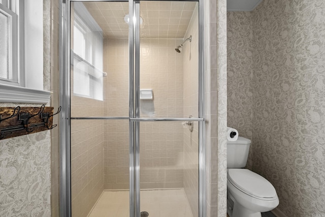 bathroom with a shower stall, wallpapered walls, and toilet