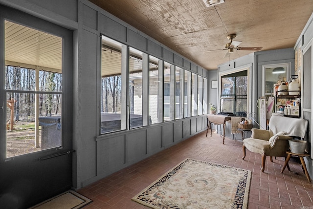 sunroom with a wealth of natural light, wood ceiling, and a ceiling fan