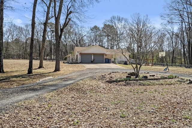 view of front of house with an attached garage, fence, and dirt driveway