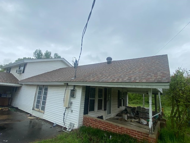 rear view of property with aphalt driveway, brick siding, and a shingled roof