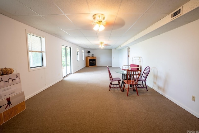 carpeted dining space featuring visible vents, a paneled ceiling, baseboards, and a fireplace