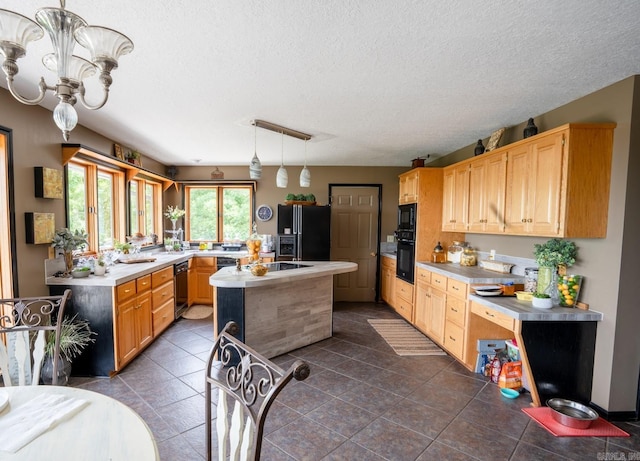 kitchen featuring black appliances, a center island with sink, light brown cabinetry, and light countertops