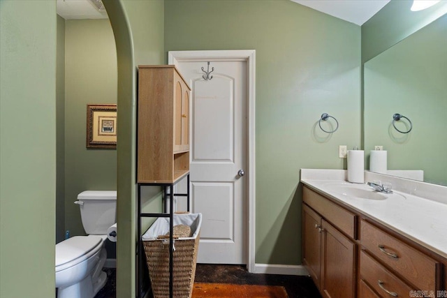 bathroom featuring baseboards, toilet, and vanity