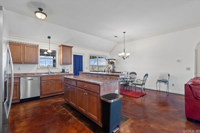 kitchen featuring brown cabinetry, lofted ceiling, appliances with stainless steel finishes, arched walkways, and a sink