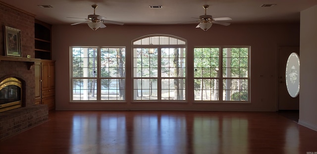 unfurnished living room with visible vents, a fireplace, and wood finished floors