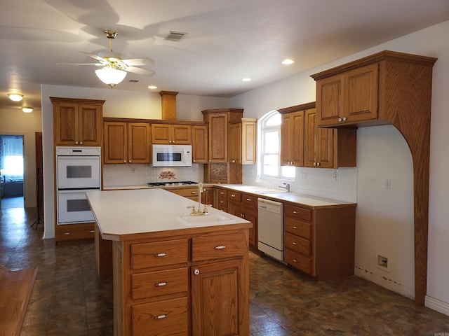 kitchen with light countertops, decorative backsplash, brown cabinetry, white appliances, and a sink