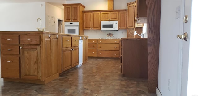 kitchen with a sink, white appliances, dark floors, and brown cabinetry