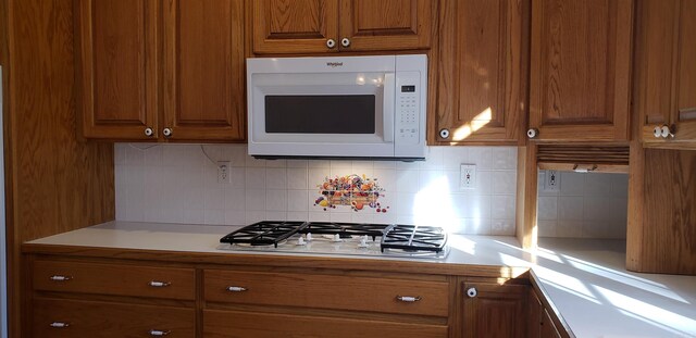 kitchen featuring white appliances and brown cabinetry