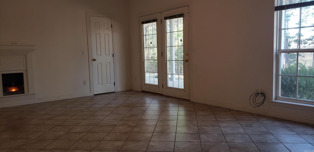 entryway with light tile patterned floors, baseboards, and a lit fireplace