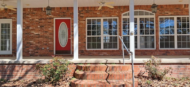 property entrance with brick siding, a porch, and a ceiling fan