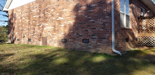 view of side of home featuring crawl space, a lawn, and brick siding