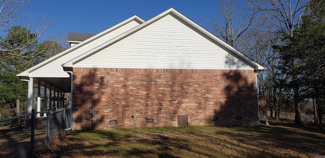 view of side of home featuring fence, a lawn, brick siding, and crawl space