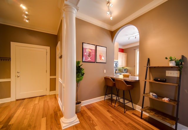 interior space featuring crown molding, light wood-style flooring, arched walkways, and ornate columns