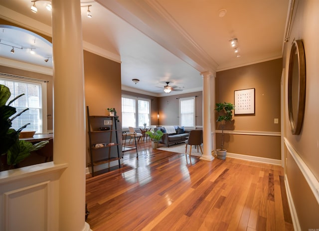 hallway with baseboards, ornamental molding, decorative columns, light wood-style flooring, and rail lighting