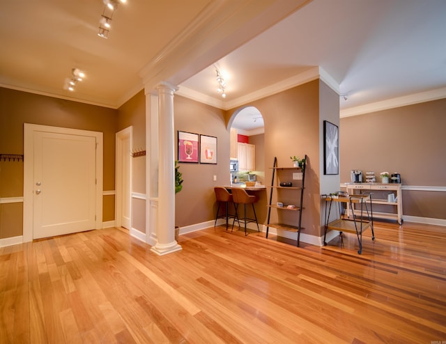 foyer featuring baseboards, wood finished floors, ornamental molding, and ornate columns