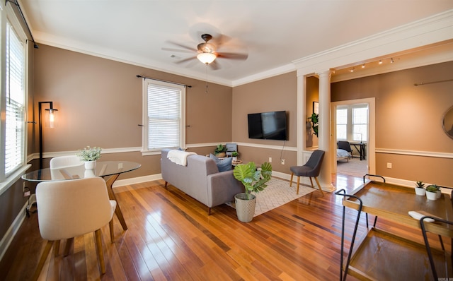 living room featuring wood finished floors, baseboards, ornate columns, ceiling fan, and crown molding