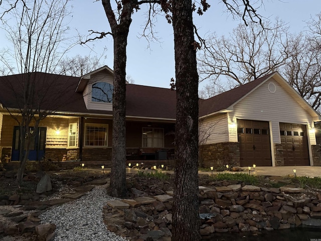 view of front of home with a garage, stone siding, and a porch