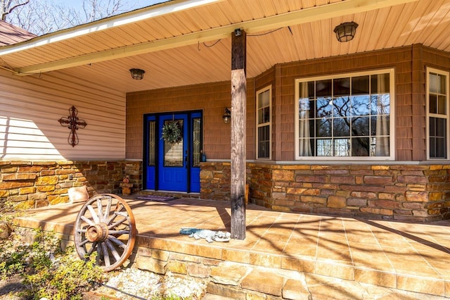 doorway to property featuring covered porch and stone siding